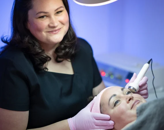 A professional therapist performing a Cryo Cool Lift Facial using the coolifting gun to rejuvenate and tighten a client's skin at Beauty by Ruth.